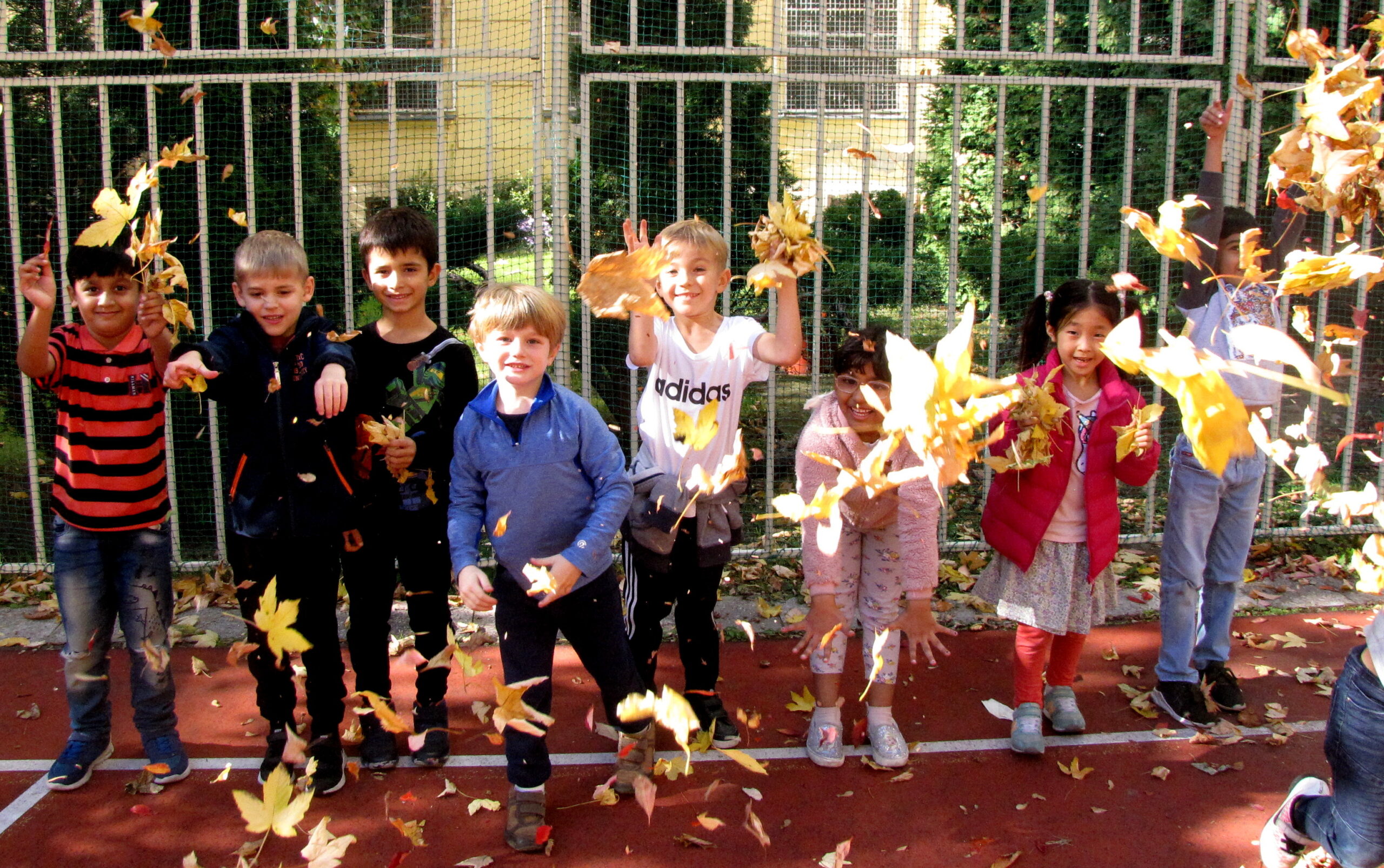 Elementary students enjoying spring, throwing up leaves.