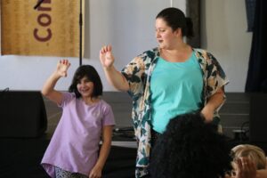 Elementary student and teacher performing hand motions to a song
